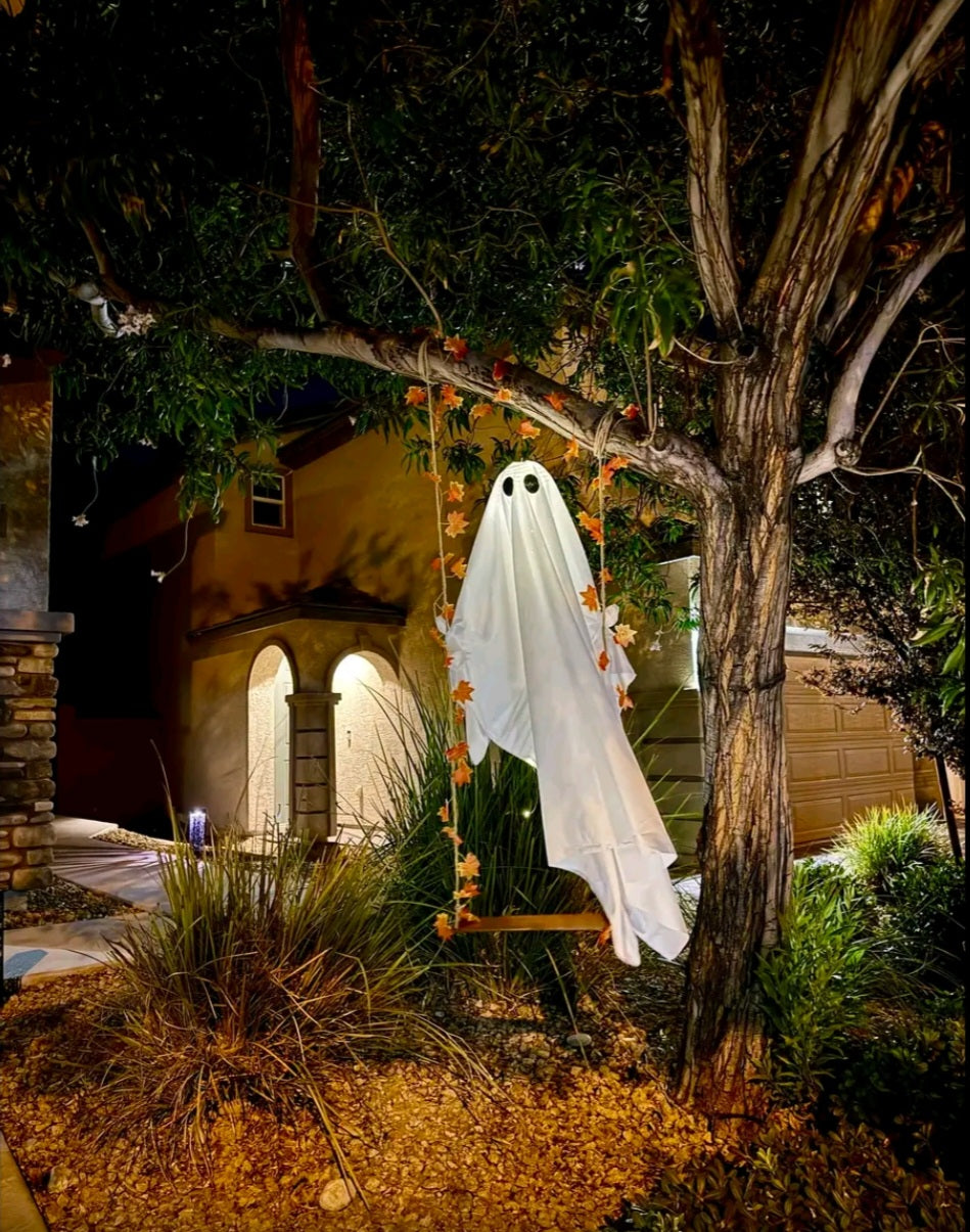 Light-up swinging ghost hanging outdoors at night